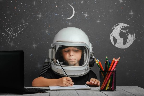 Criança estudando com capacete de astronauta - Mamãe Retrô